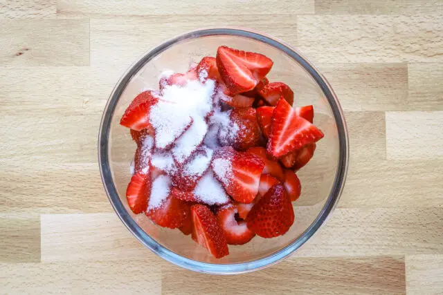 Strawberries and sugar in a glass bowl.