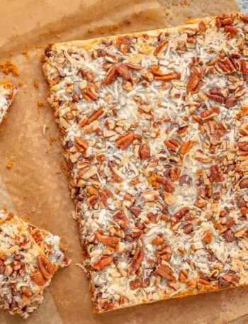 baked magic cookie bars on parchment paper, sliced