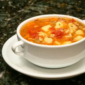 a bowl of manhattan clam chowder with tomatoes, bacon, and potatoes