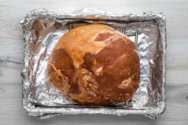 Ham is scored and placed on a rack in the foil-lined baking pan.