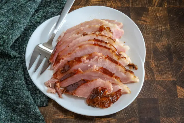 Sliced maple and brown sugar glazed ham on a serving platter.