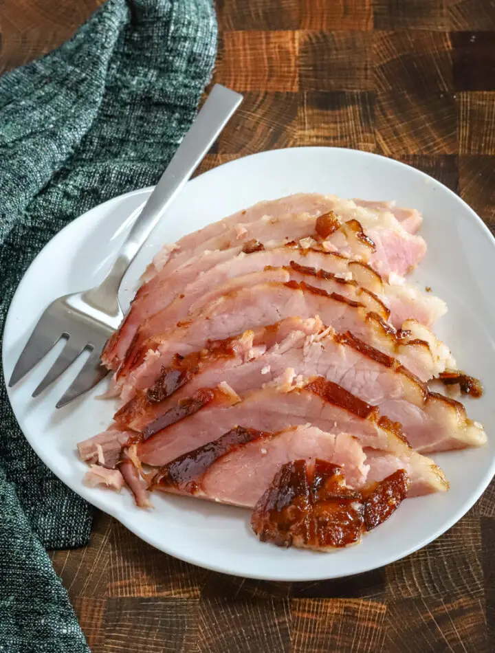 Sliced maple and brown sugar glazed ham on a serving platter.