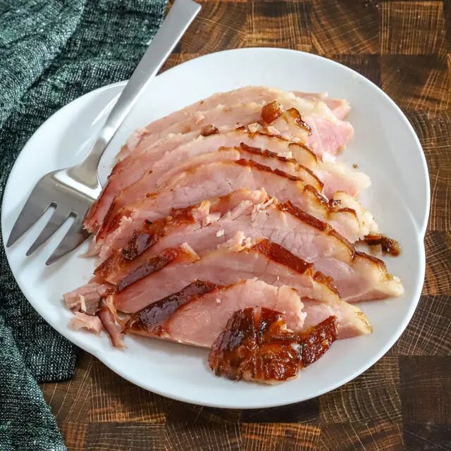 Sliced maple and brown sugar glazed ham on a serving platter.