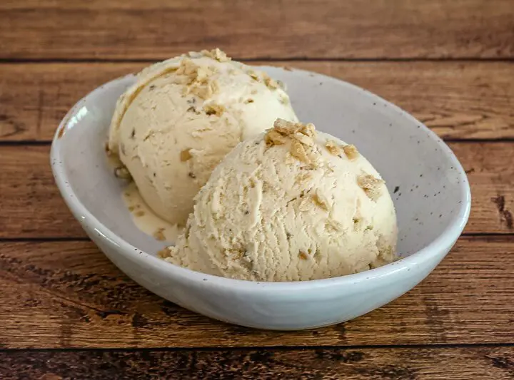 maple walnut ice cream in a bowl with maple flakes garnish