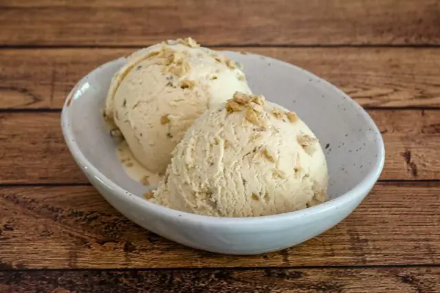 maple walnut ice cream in a bowl with maple flakes garnish