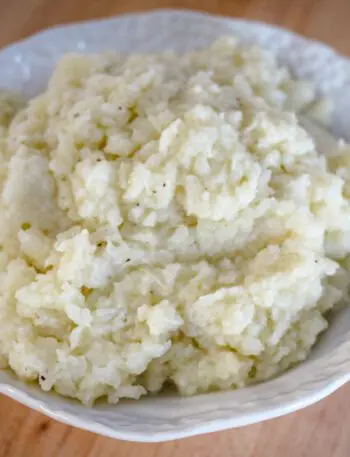 A bowl of fluffy mashed cauliflower made with butter, cream, garlic, and seasonings.