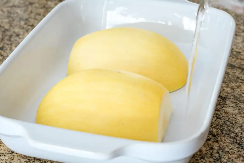 Spaghetti squash in a microwave-safe baking dish with water added.