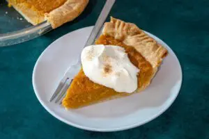 A slice of sweet potato pie with whipped cream garnish.