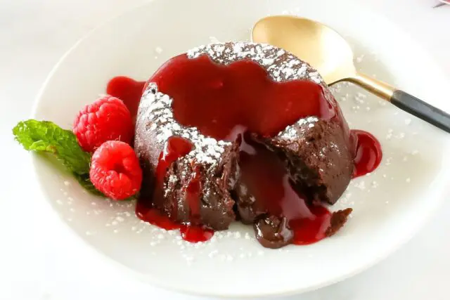 chocolate molten lava cake on a plate with raspberries and mint