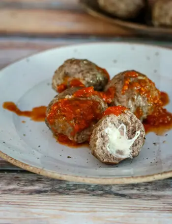 Mozzarella stuffed meatballs with marinara sauce on a plate.