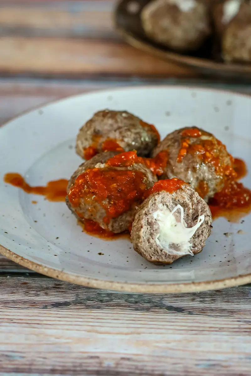 Mozzarella stuffed meatballs with marinara sauce on a plate.