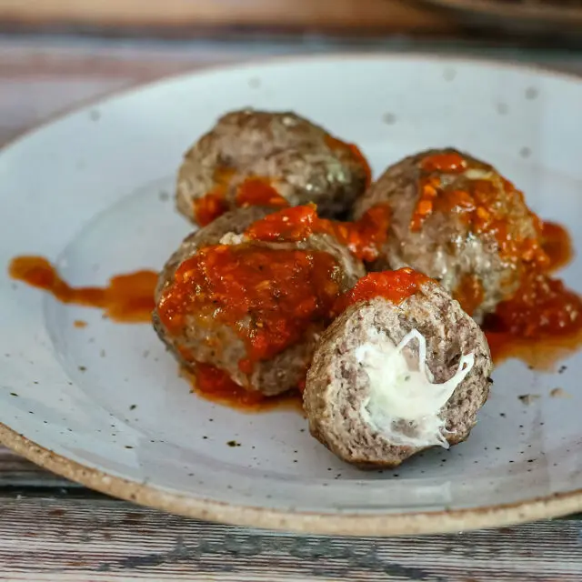 Mozzarella stuffed meatballs with marinara sauce on a plate.