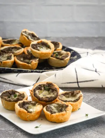 Mushroom tartlets being served with a scattering of thyme.