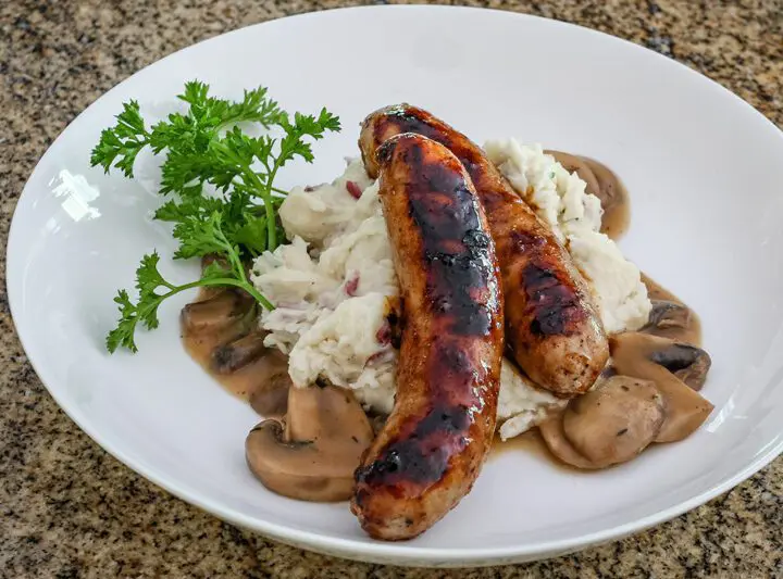 Mushroom sauce with beef stock, garlic, and a splash of beer shown with mashed potatoes and grilled sausages.