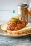 Plate of Nashville hot chicken on bread with pickles.