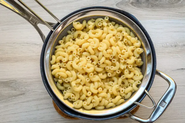 Mac and cheese prep: draining the macaroni.