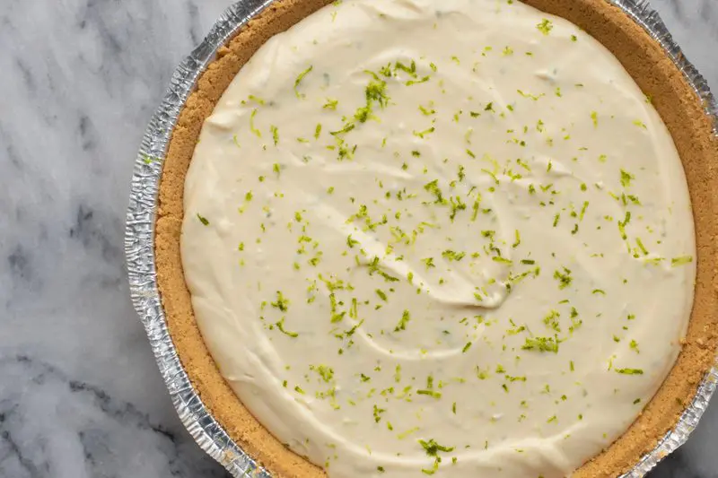 A whole no-bake key lime cheesecake with lime zest.