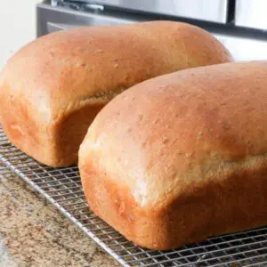 Two loves of oatmeal bread on a cooling rack.