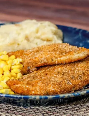 Panko crusted oven fried chicken on a plate with mashed potatoes and corn.