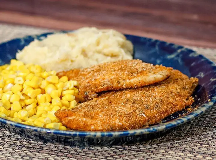 Panko crusted oven fried chicken on a plate with mashed potatoes and corn.