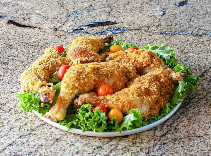 Cornflake crusted chicken on a platter with tomatoes and lettuce.