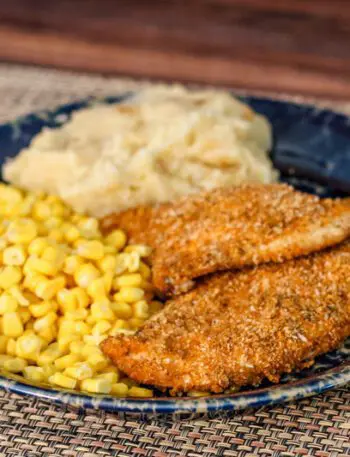 spiced oven fried chicken on a plate with potatoes and corn