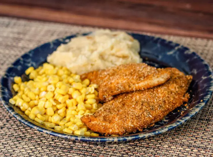 spiced oven fried chicken on a plate with potatoes and corn