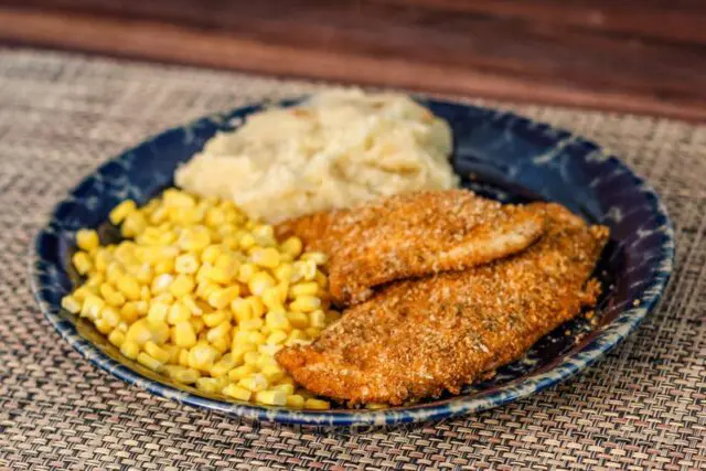 spiced oven fried chicken on a plate with potatoes and corn