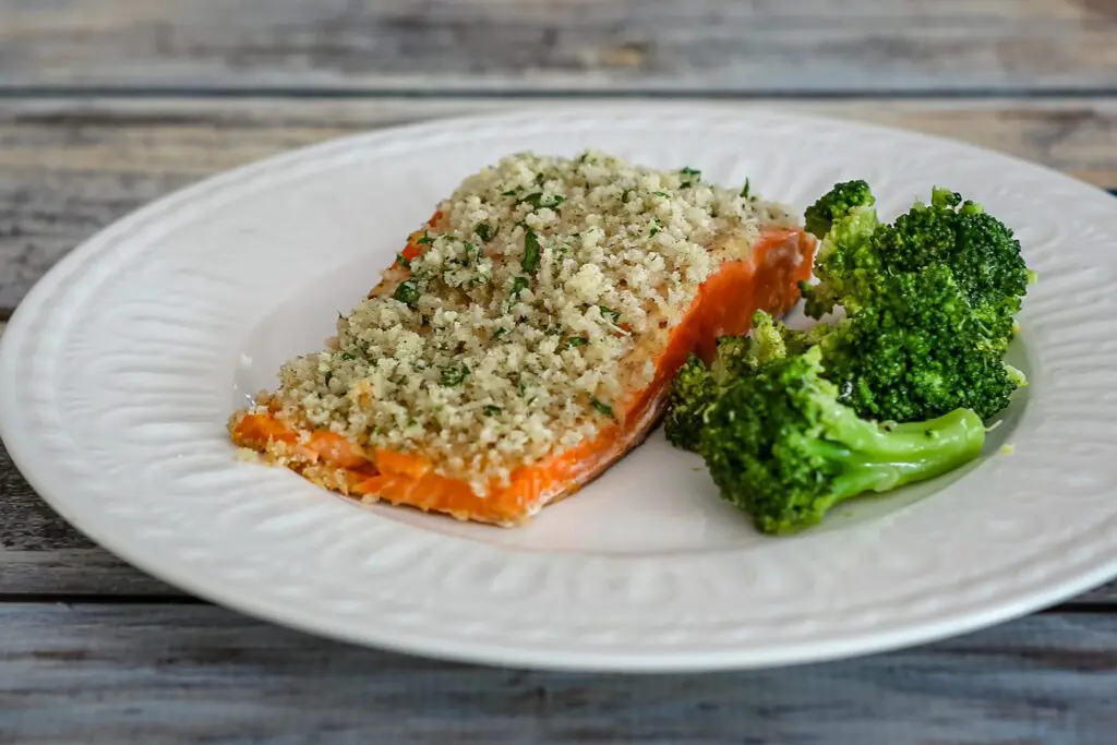 salmon fillet on a plate with Dijon mustard and panko crust  and broccoli on the side
