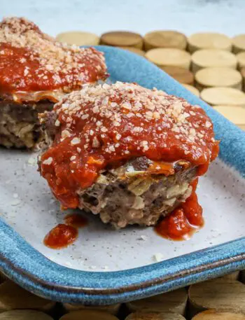 parmesan meatloaf in muffin shapes, topped with pizza sauce and extra parmesan cheese