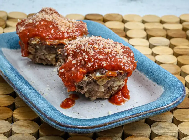 parmesan meatloaf in muffin shapes, topped with pizza sauce and extra parmesan cheese