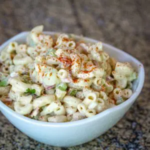 Pasta salad in a bowl with cucumbers and ham.