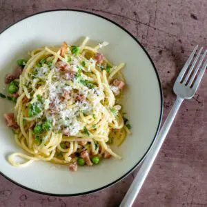 spaghetti with pancetta and peas along with a garnish of pecorino romano or parmesan