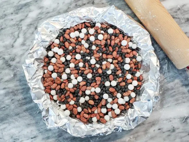 Blind baking is recommended for many pies. Here the butter crust is shown with foil protection and a mixture of pie weights and dry beans.