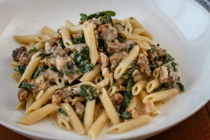 closeup picture of penne pasta with sausage and spinach