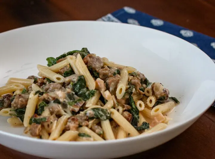 Creamy penne with sausage and spinach in a bowl