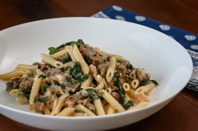 Creamy penne with sausage and spinach in a bowl