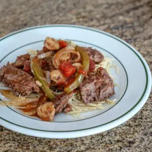 A serving of comforting pepper steak on noodles.