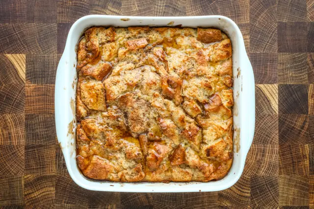 Baked French toast casserole in the baking dish with a drizzle of maple syrup.