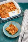 A baked French toast casserole serving with maple syrup and the casserole dish in the background.