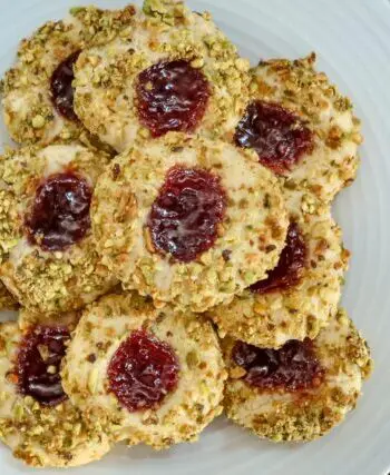 pistachio thumbprint cookies with jam center, arranged on a plate