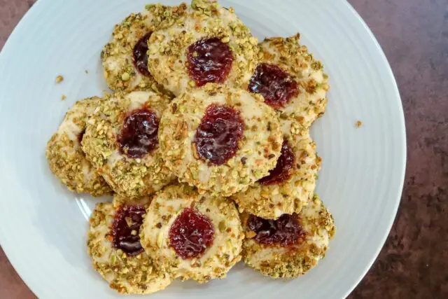 pistachio thumbprint cookies with jam center, arranged on a plate