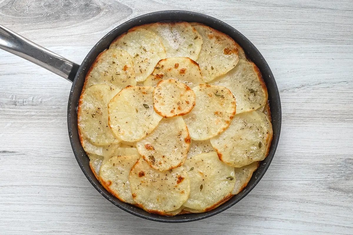 Pommes anna in the skillet, ready to flip.