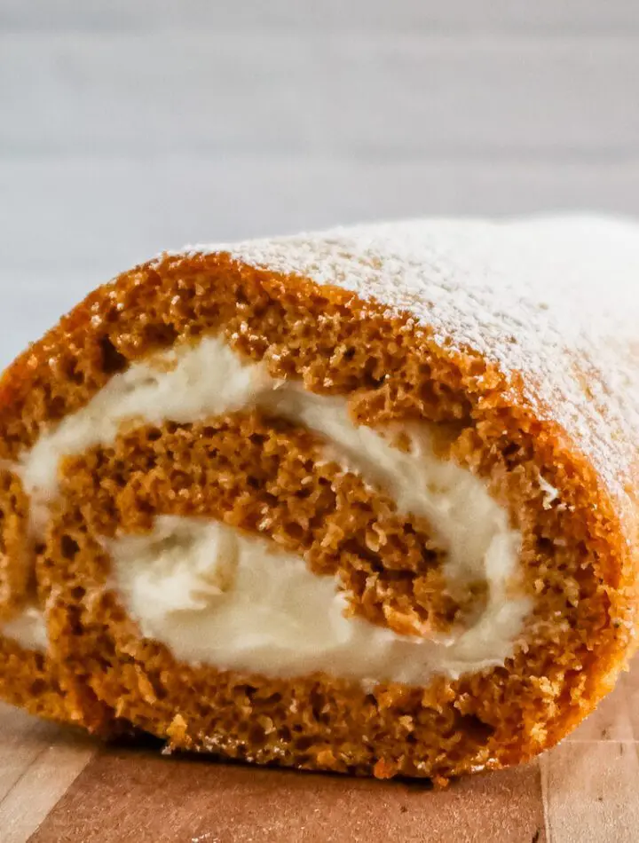 pumpkin cake roll with cream cheese filling on a cutting board