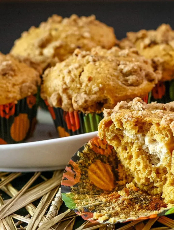 dish with pumpkin cream cheese muffins and one cut in half