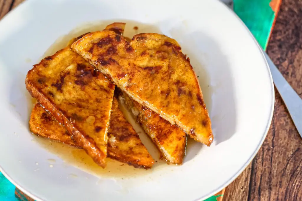A serving of 2 slices of pumpkin French toast with syrup.