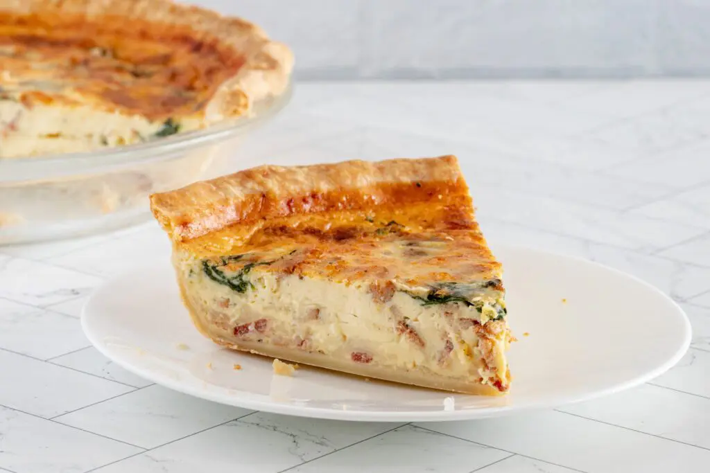 A slice of quiche lorraine with spinach and bacon