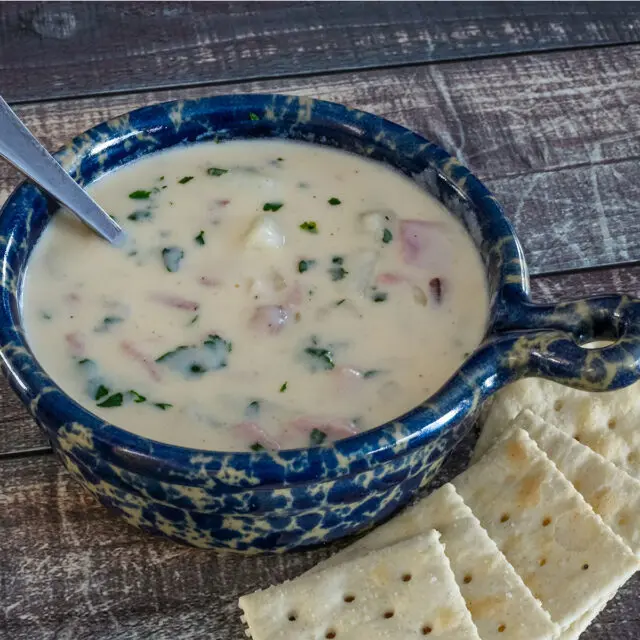 A bowl of potato soup with spoon.