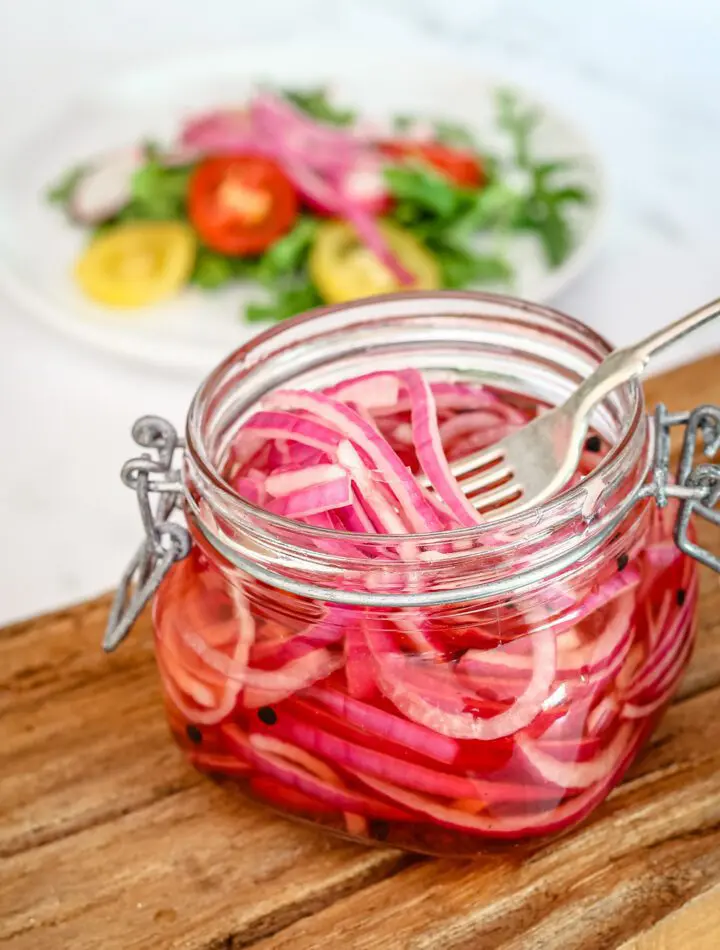 quick pickled onions in a canning jar with a salad in the background