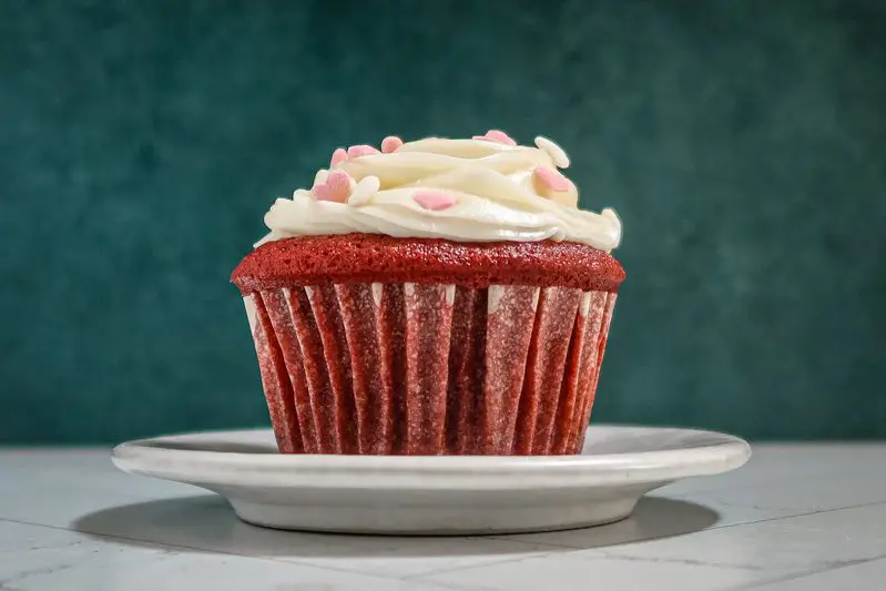 a red velvet cupcake with little heart decorations on the frosting.